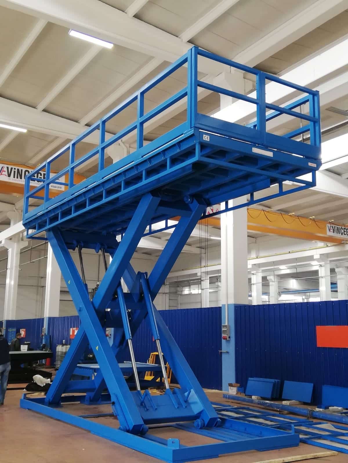 Blue scissor lift table in an industrial manufacturing environment
