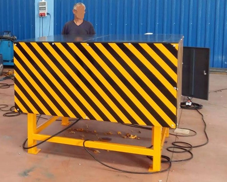 Ein Mann steht vor einer Maschine mit gelbem Streifen und zeigt Unterlaufschutz